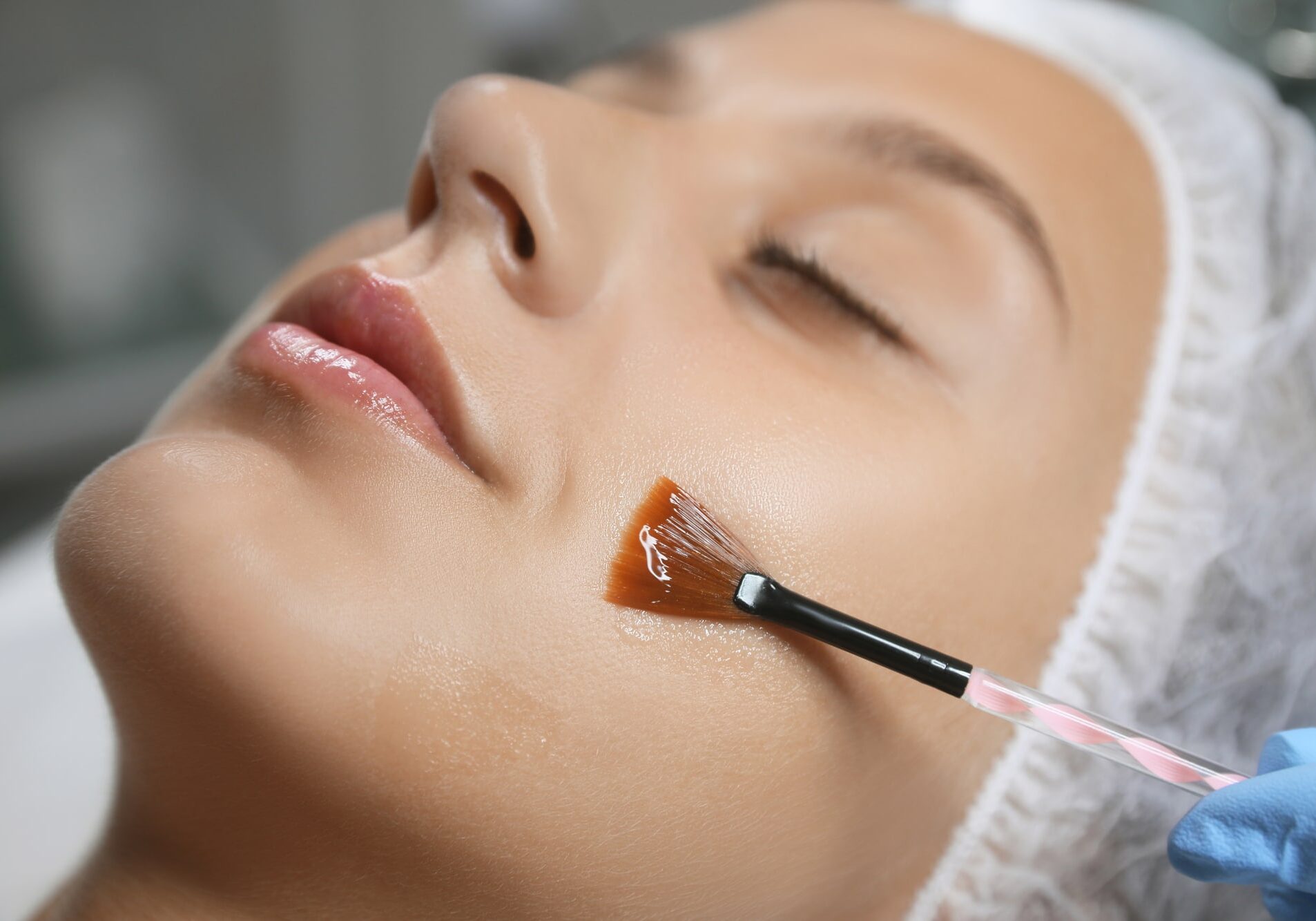 Young woman during face peeling procedure in salon, closeup